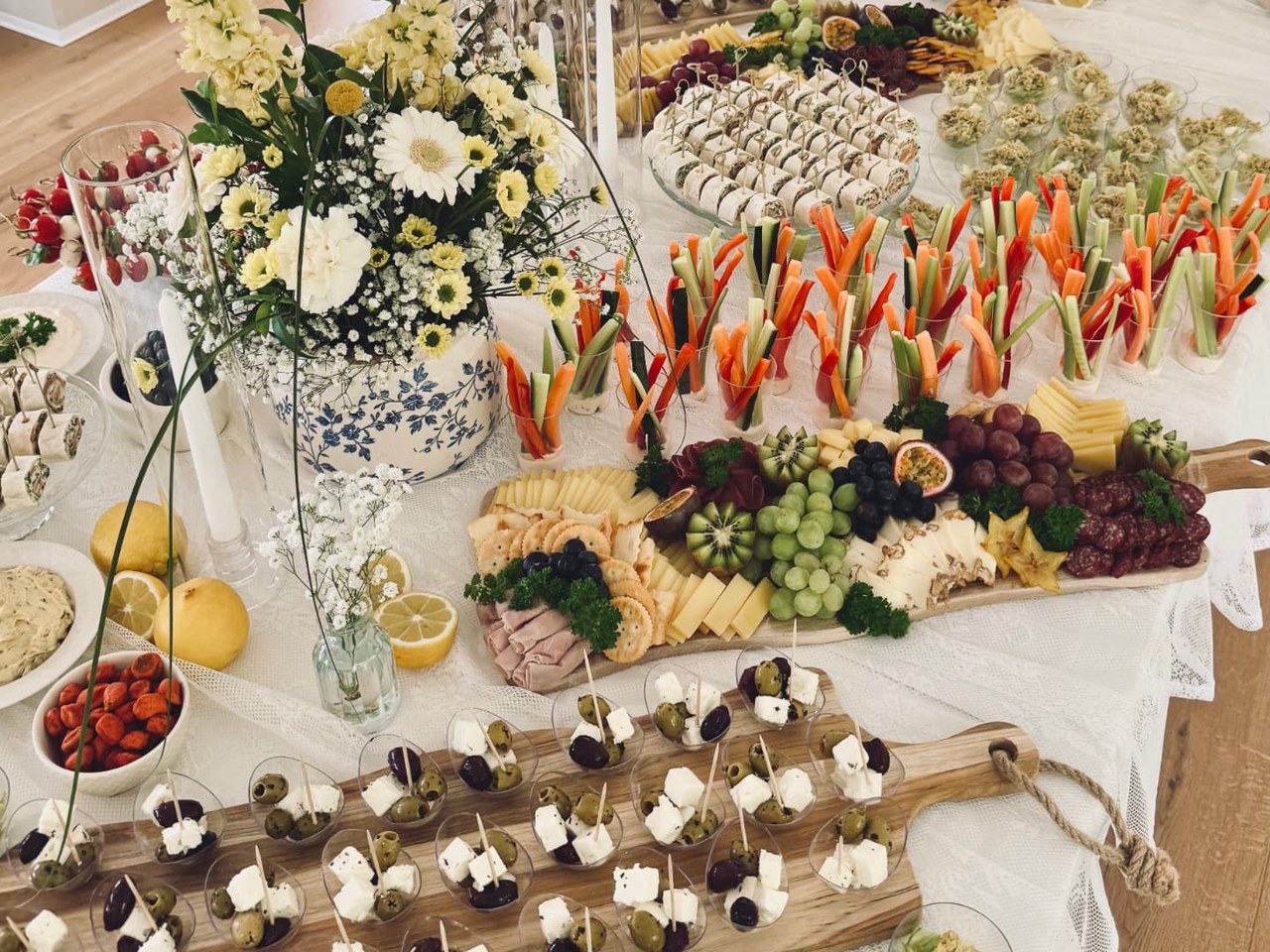 Gedecktes Apéro-Buffet mit Gemüsesticks, Früchteplatte, Käse und Feta-Oliven-Spiessen in einem hellen Raum