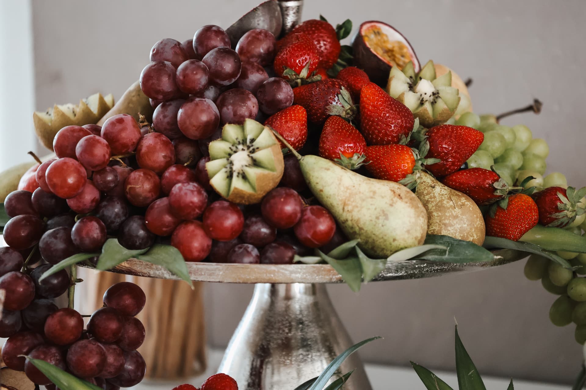 Silberne Etagere reich arrangiert mit Trauben, Erdbeeren, Birnen und Kiwis
