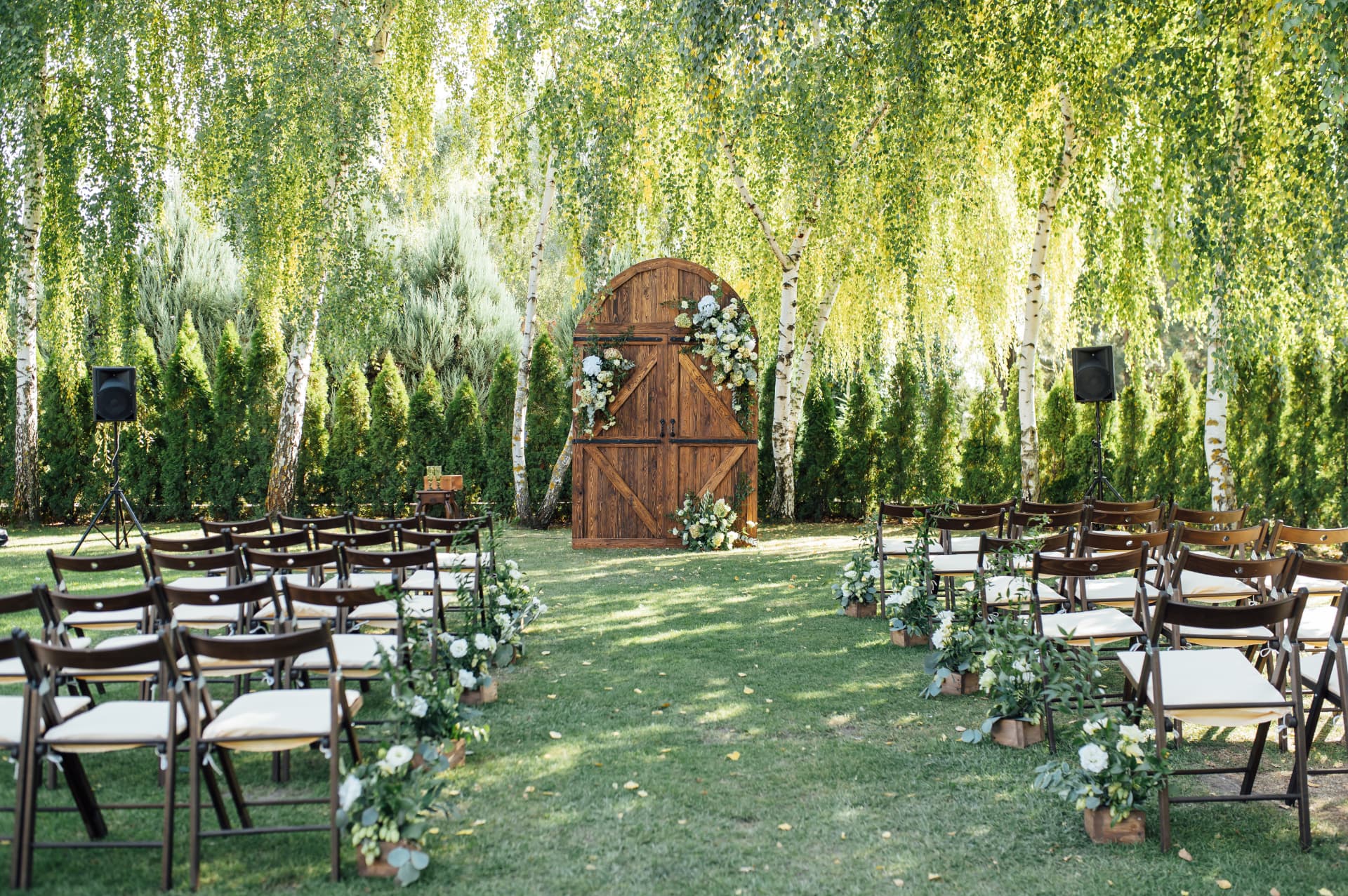 Hochzeitszeremonie im Freien mit Holztür, Blumen und Birken