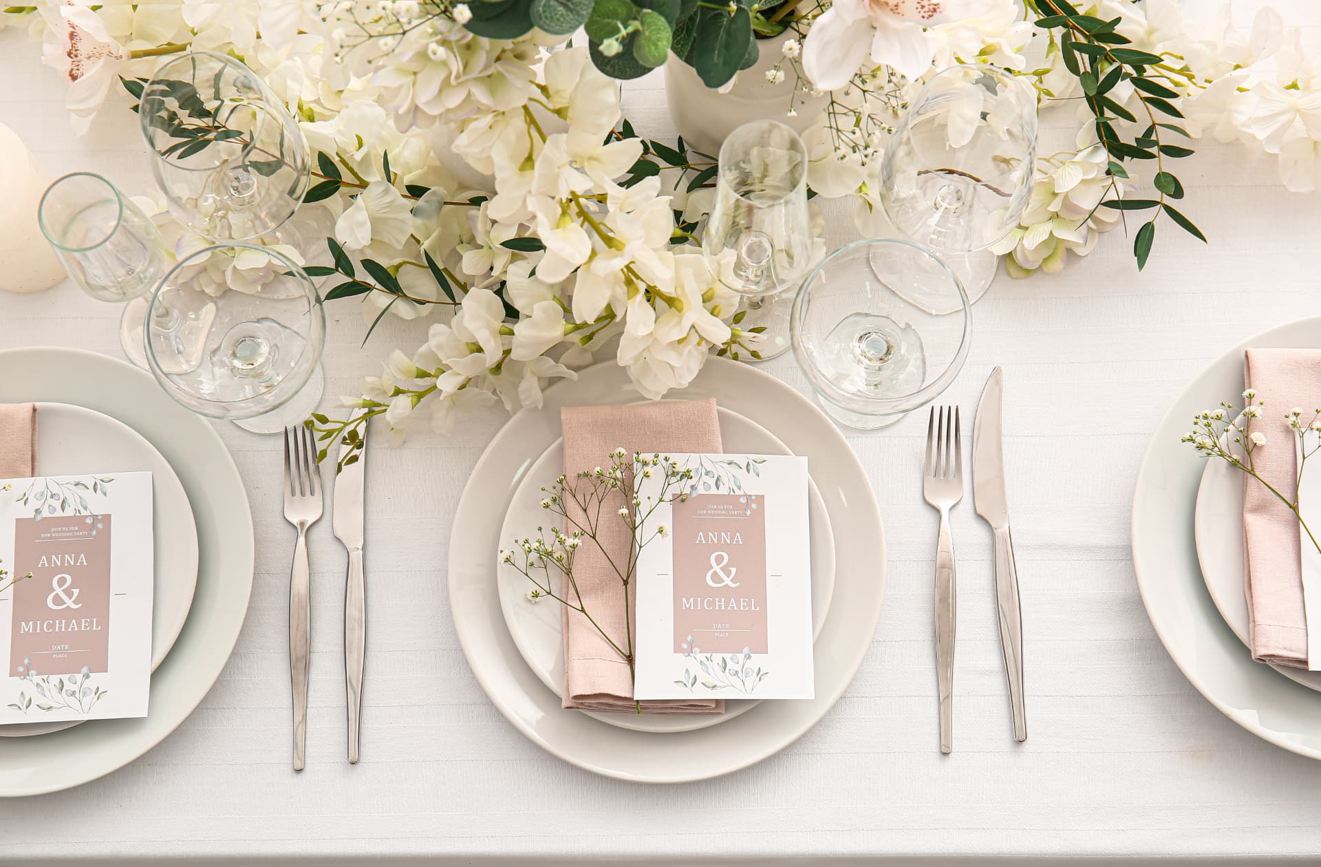 Festlich gedeckter Hochzeitstisch mit weissen Tellern, altrosafarbenen Servietten und weissen Blumen mit Eukalyptus