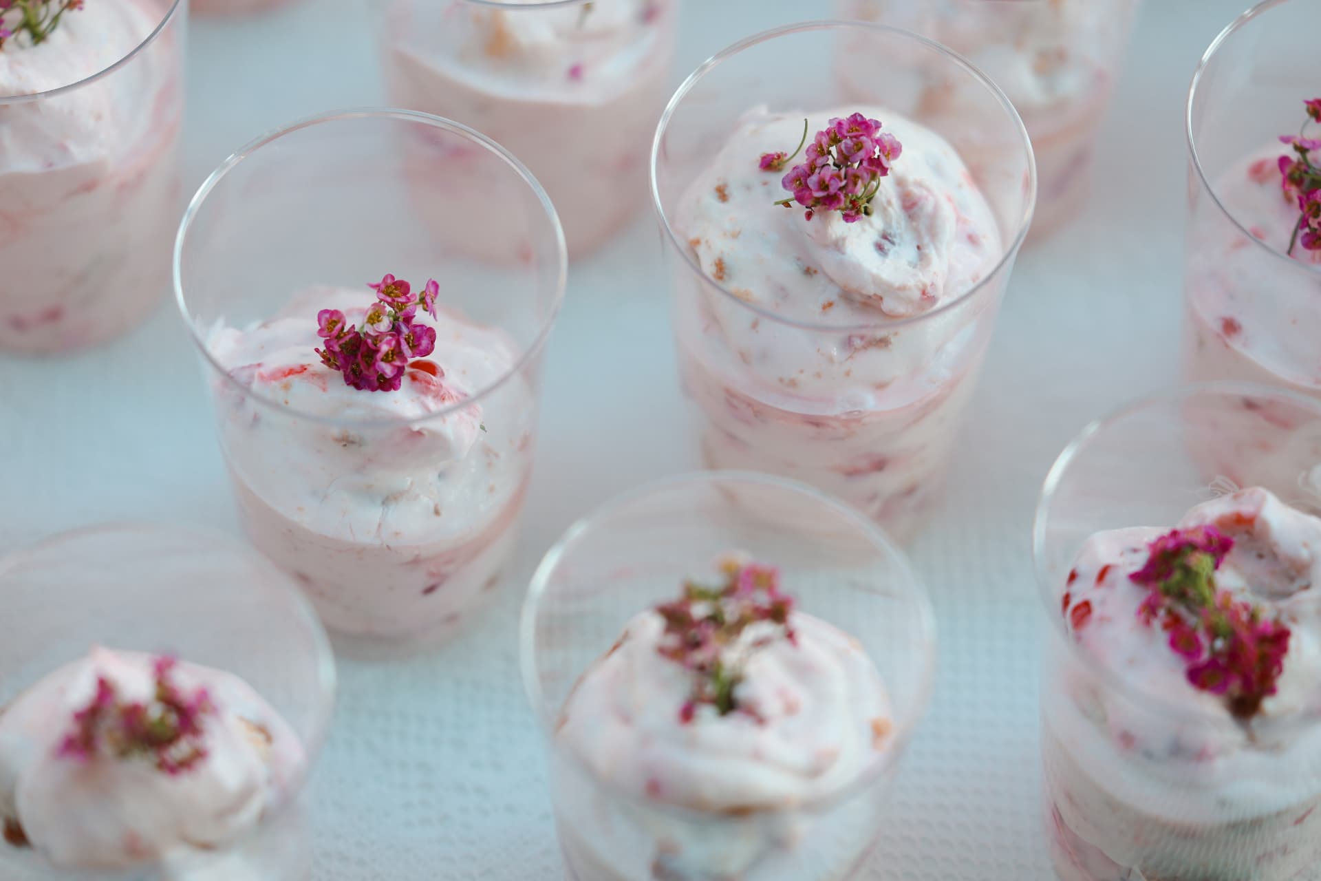 Hohe Dessertbecher mit marmorierter Beerencreme und essbaren Blüten